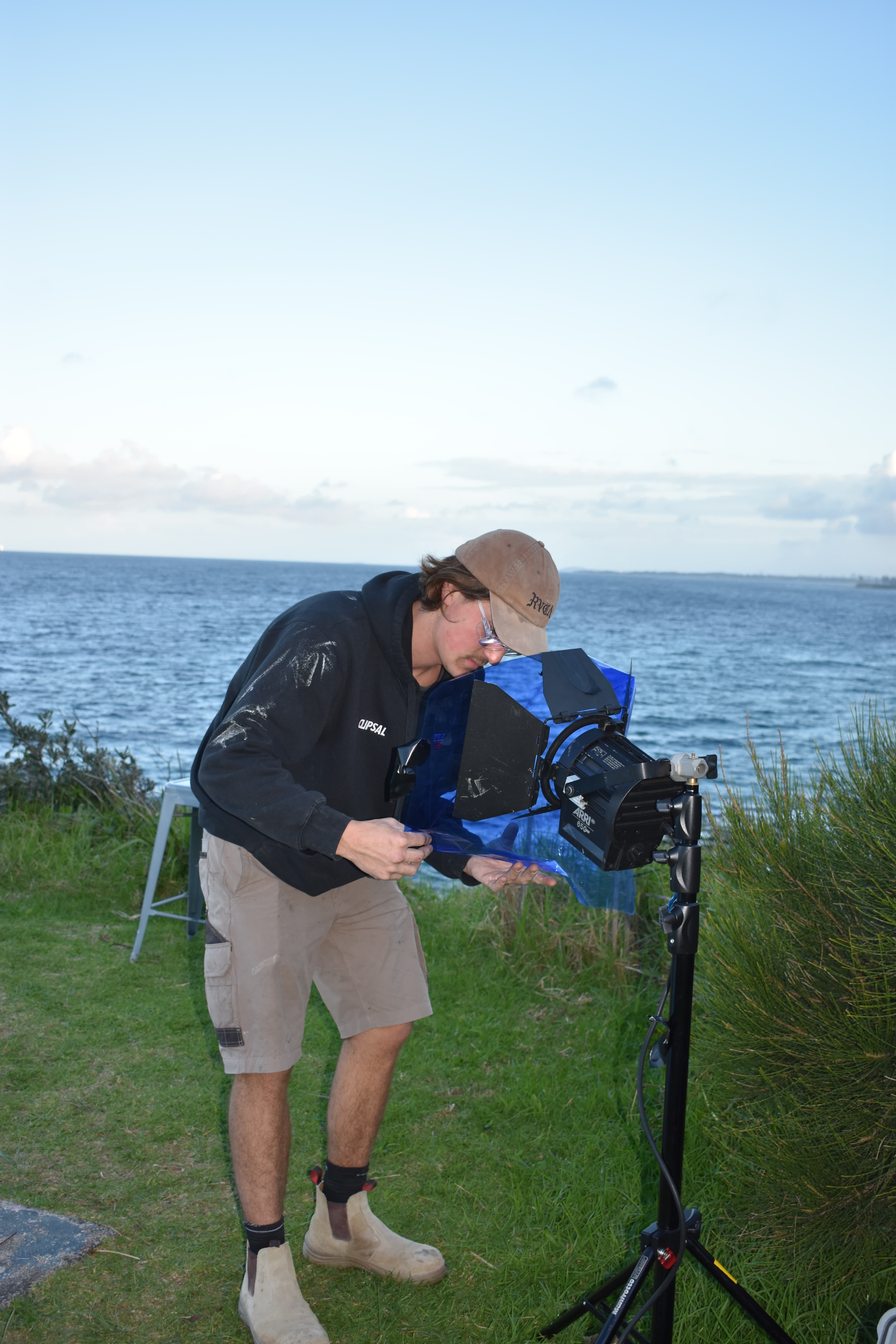 Denim Budai adjusting a light rig on set