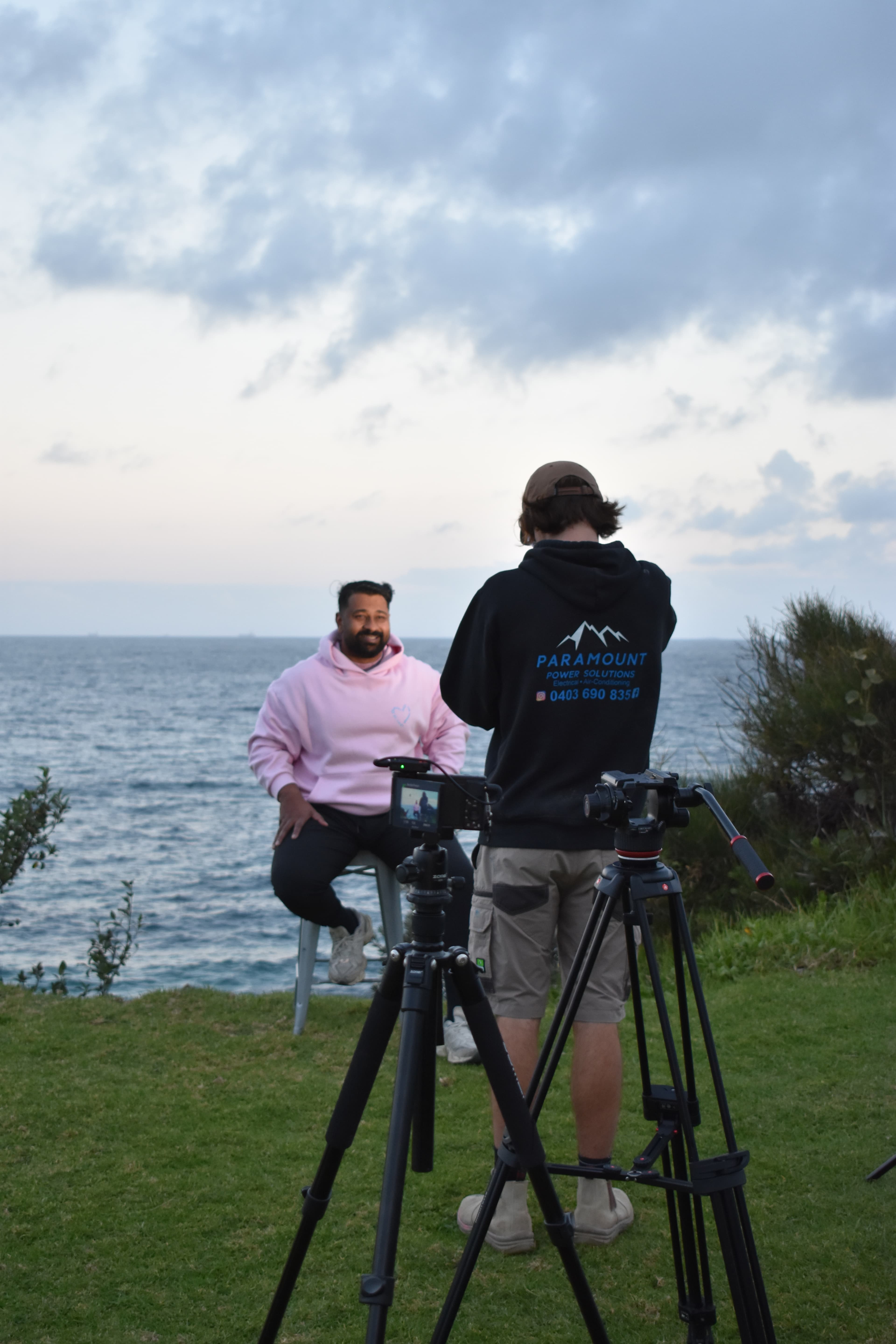 Denim Budai filming an on-camera interview by the coast