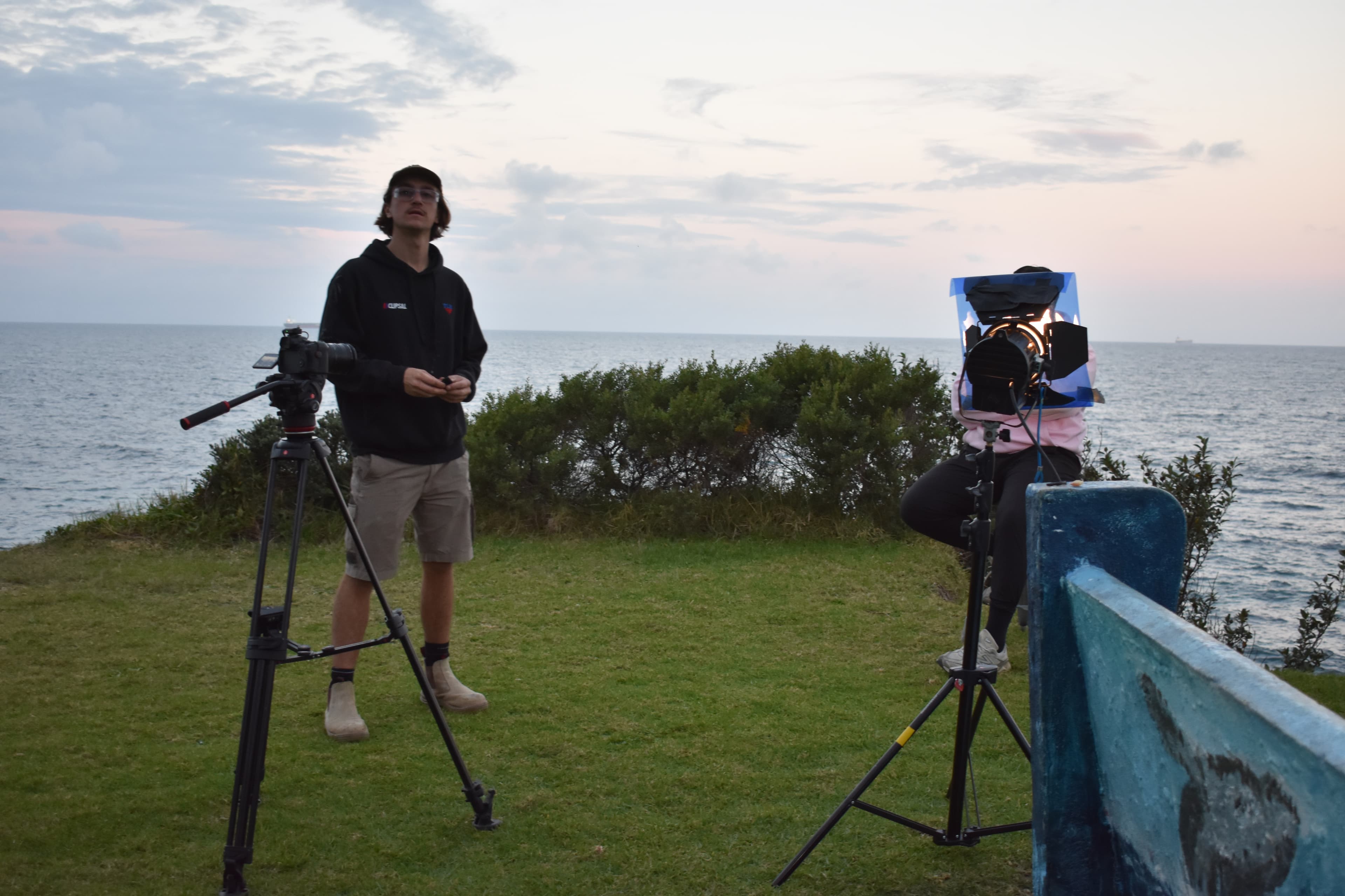 Denim Budai on set with camera and tripod overlooking the ocean